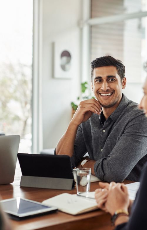 Shot of a handsome young businessman smiling during a meeting with colleagues at w